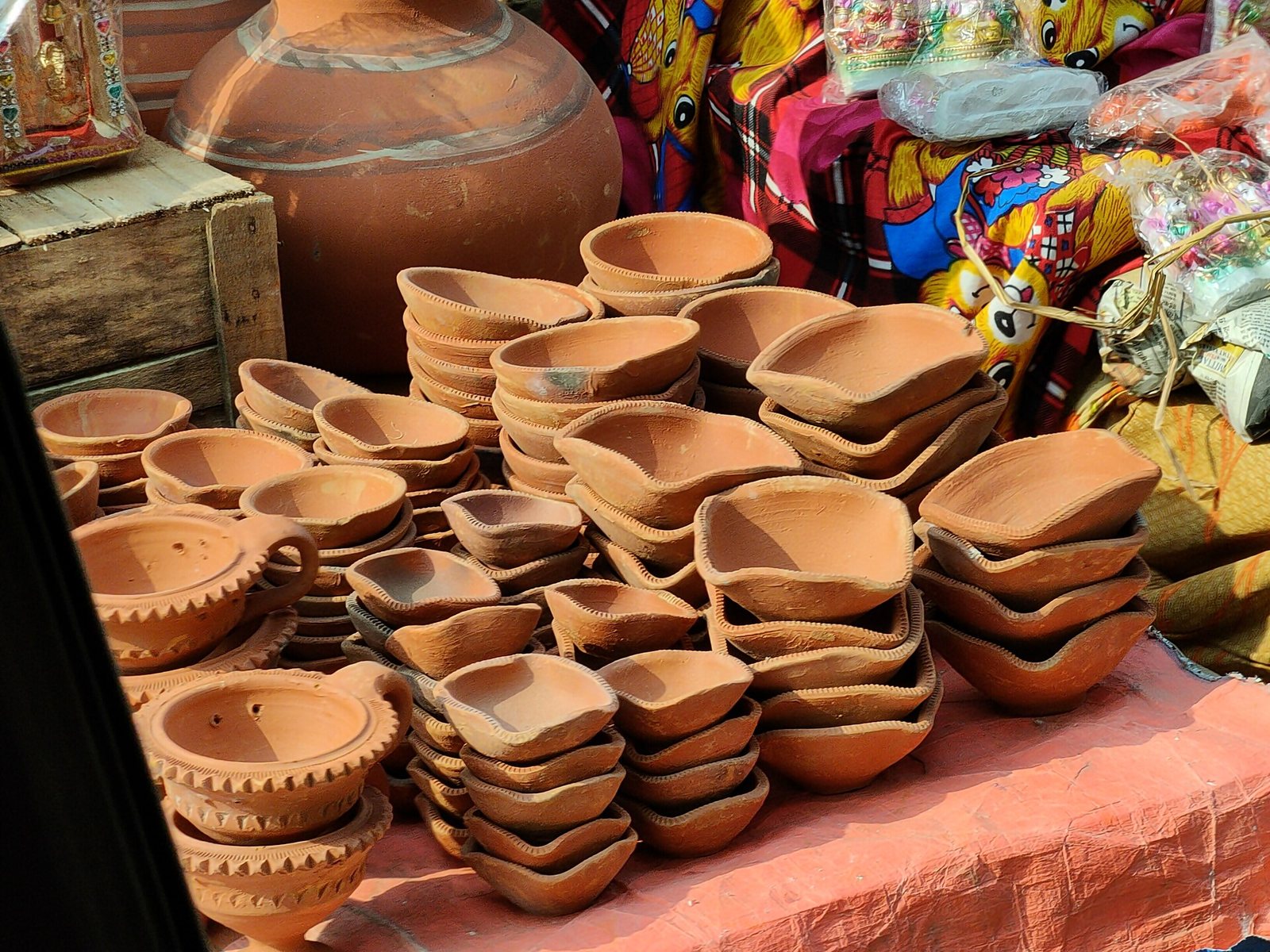 Stacks of handmade clay diyas for sale at a festival market