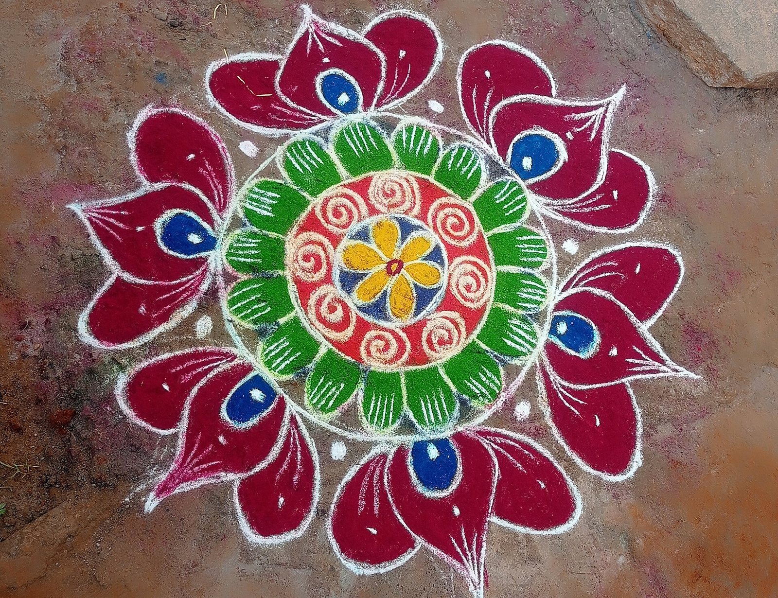A colourful rangoli pattern drawn in coloured powder
